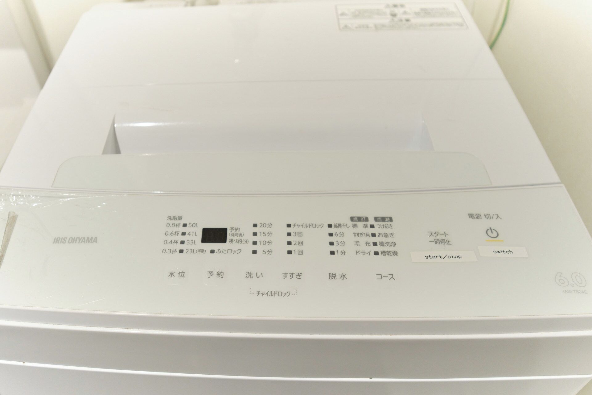 Een witte, compacte, moderne printer met Japanse tekst en symbolen op het voorpaneel, die verschillende functies en instellingen aangeven.