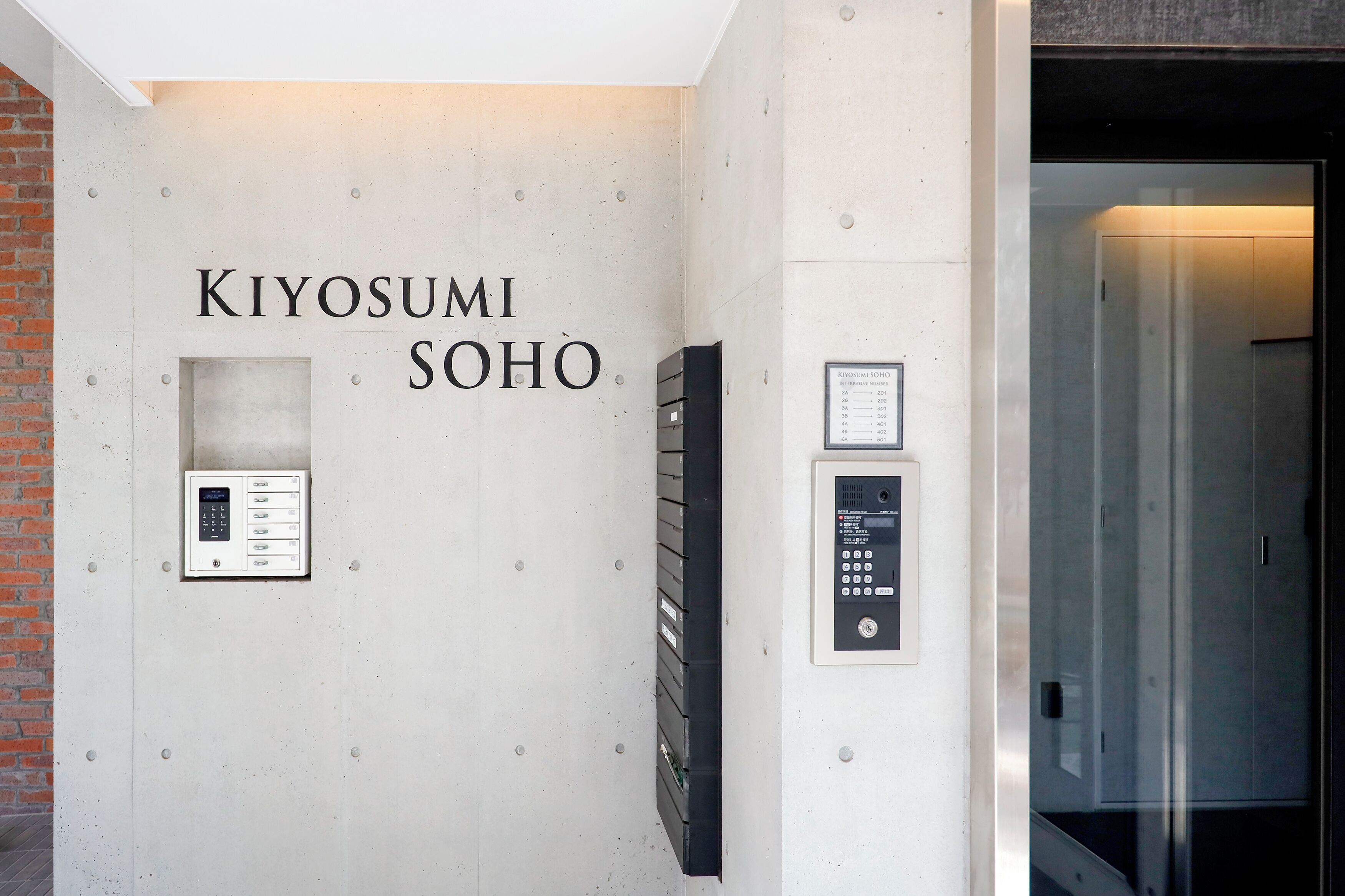 A wall with the text "KIYOSUMI SOHO" and two elevator control panels.