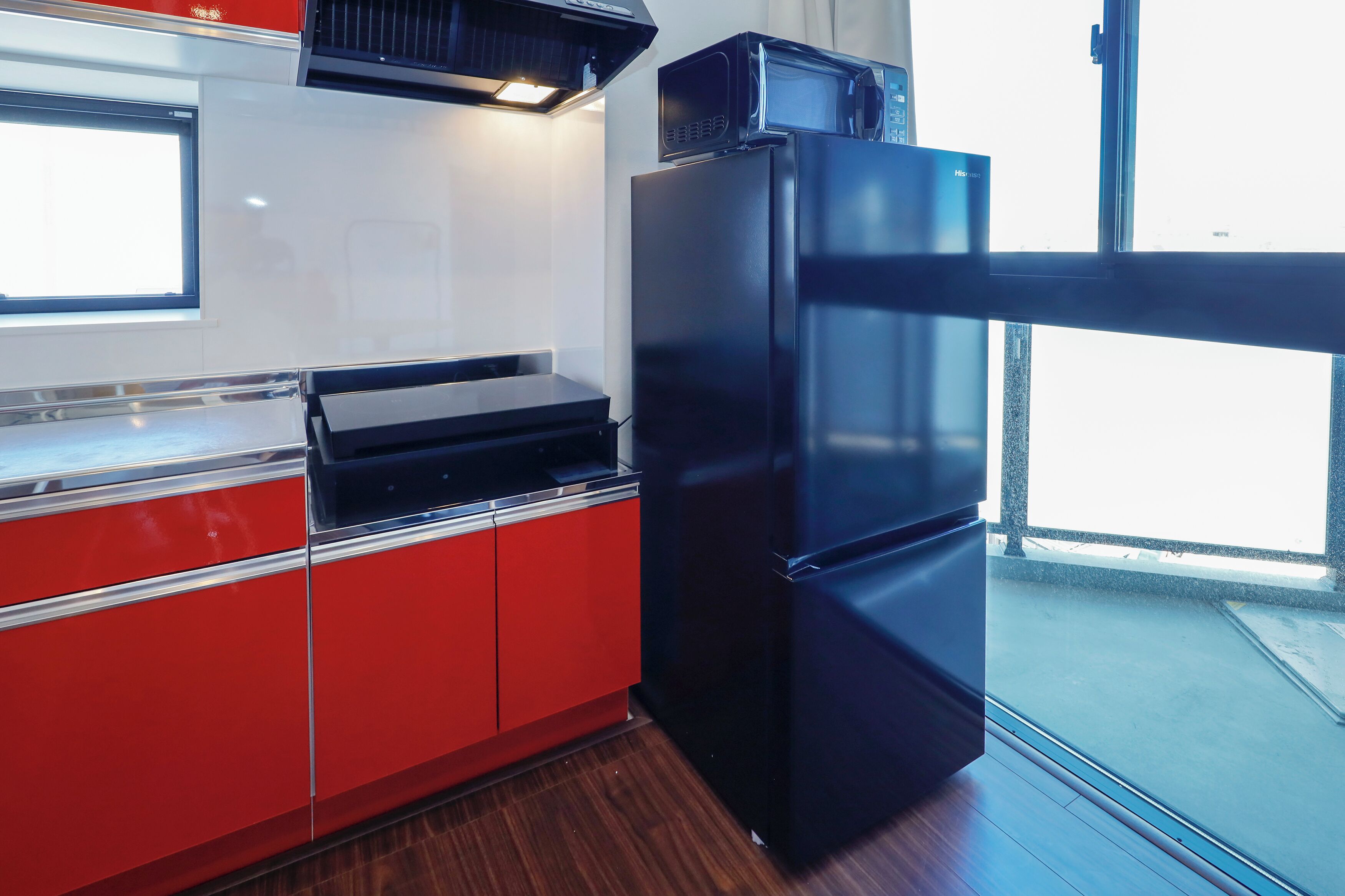 Una cocina moderna con armarios rojos, un refrigerador negro y un microondas encima.
