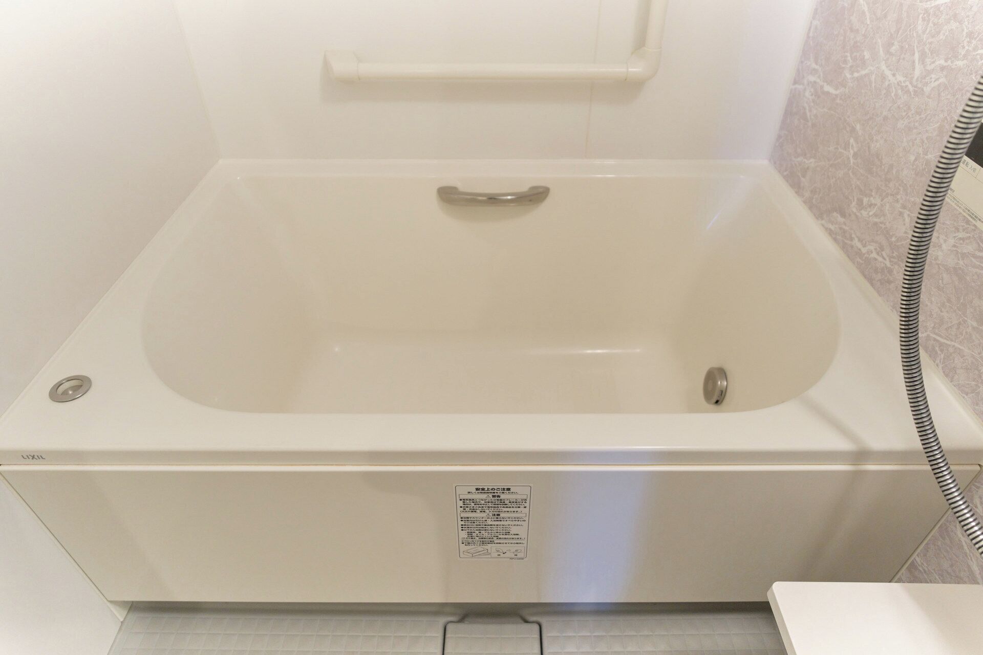 A white bathtub with a control panel and a drain.