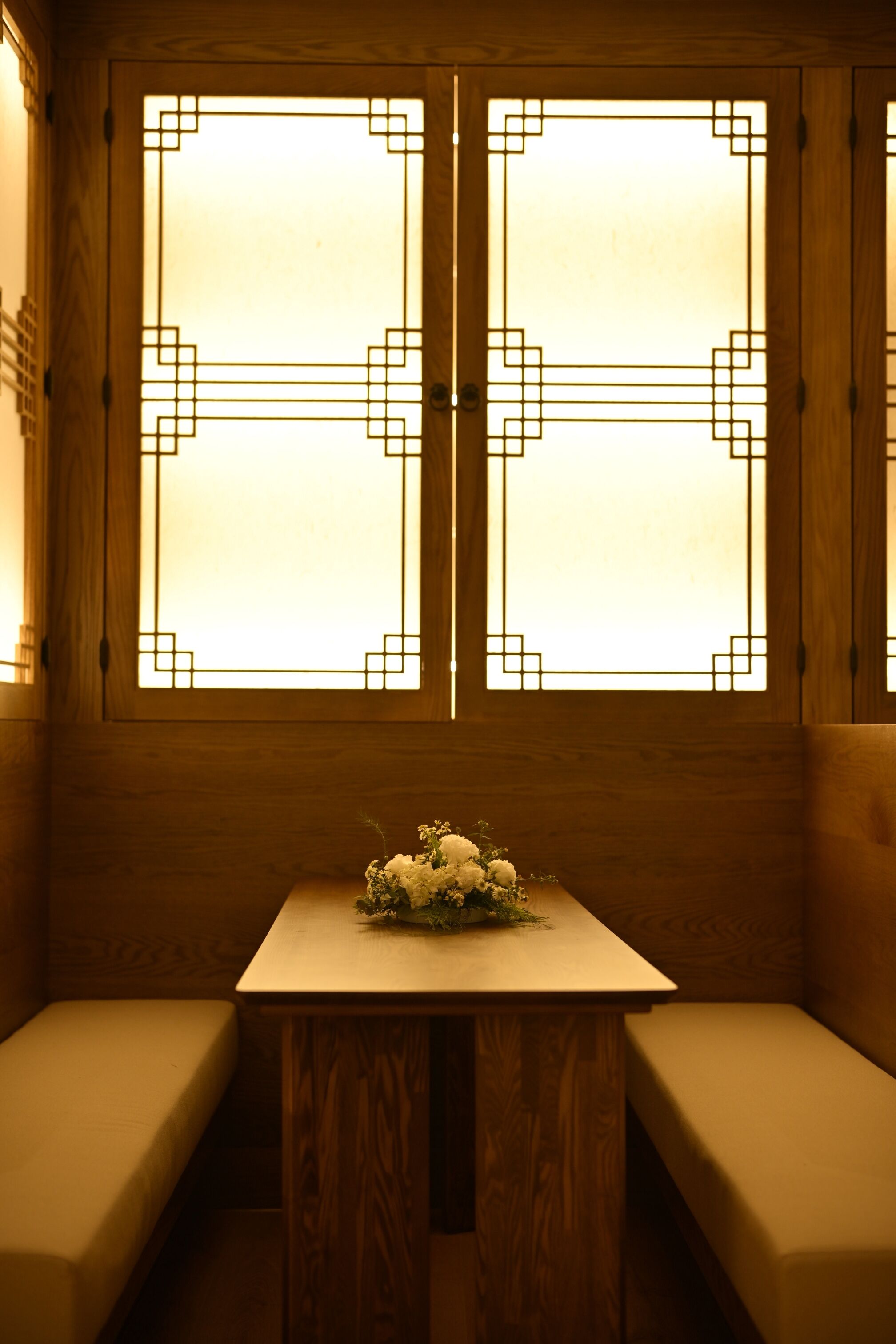 A room with wooden paneling, a bench, and a table with a floral arrangement.