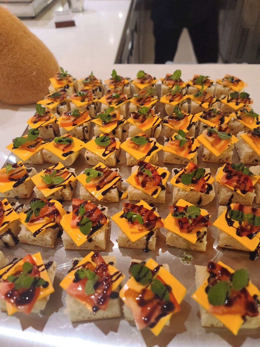 A table with square appetizers arranged in rows.