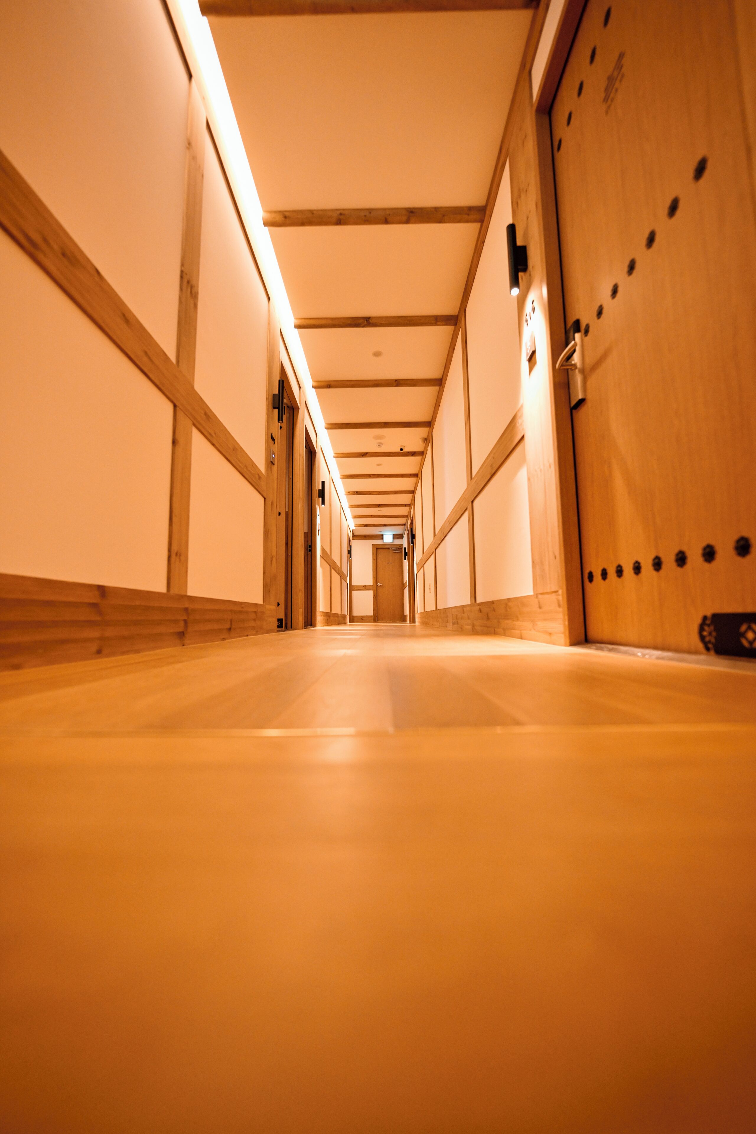 Un pasillo con paredes y piso de madera, que conduce a una puerta al final.