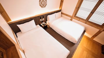 Una habitación con dos camas, cabeceros de madera, un adorno en la pared y una mesita de noche con un teléfono.