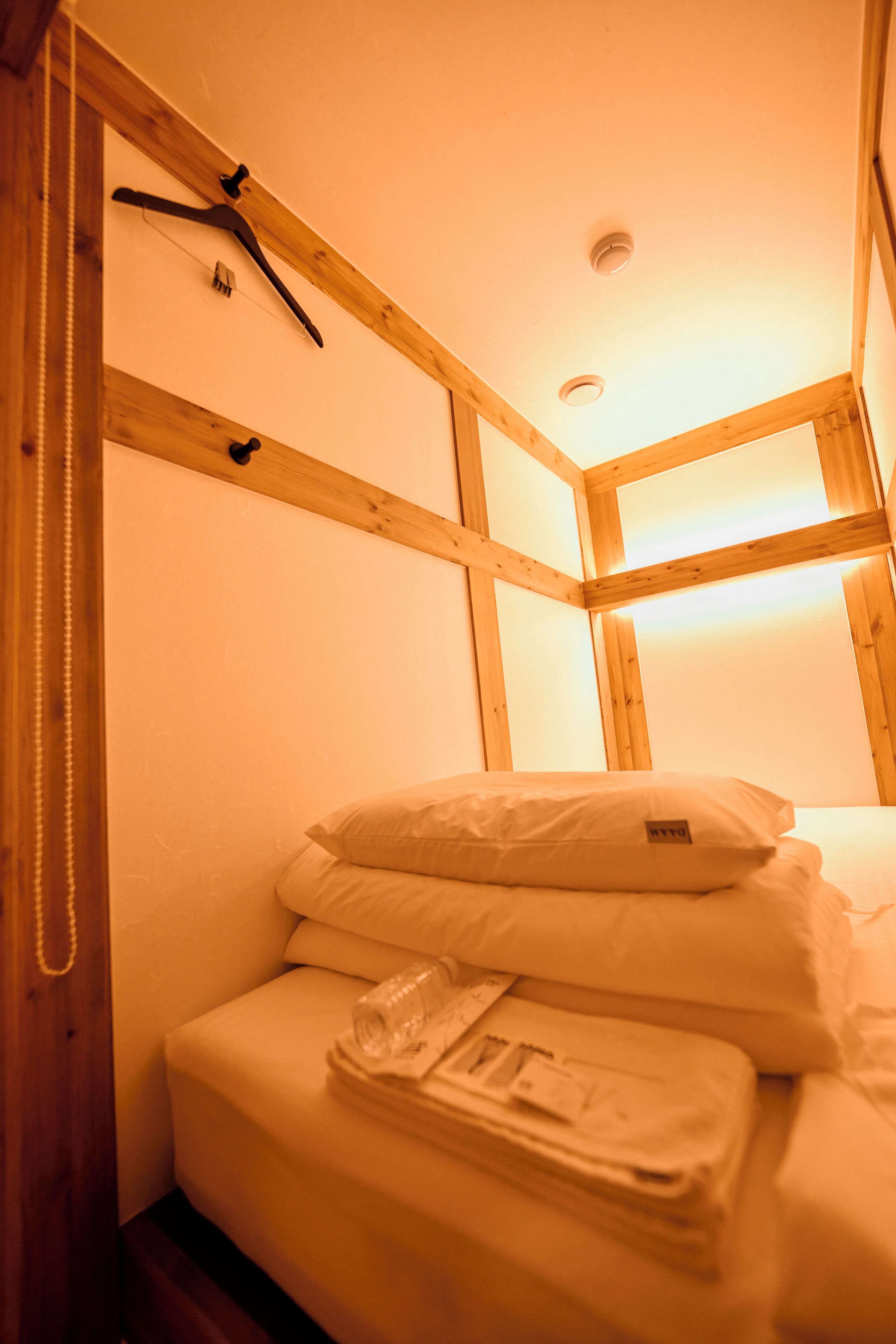 Une petite pièce agréable et chaleureuse, avec un plafond en bois et un lit bien fait, recouvert de draps blancs.