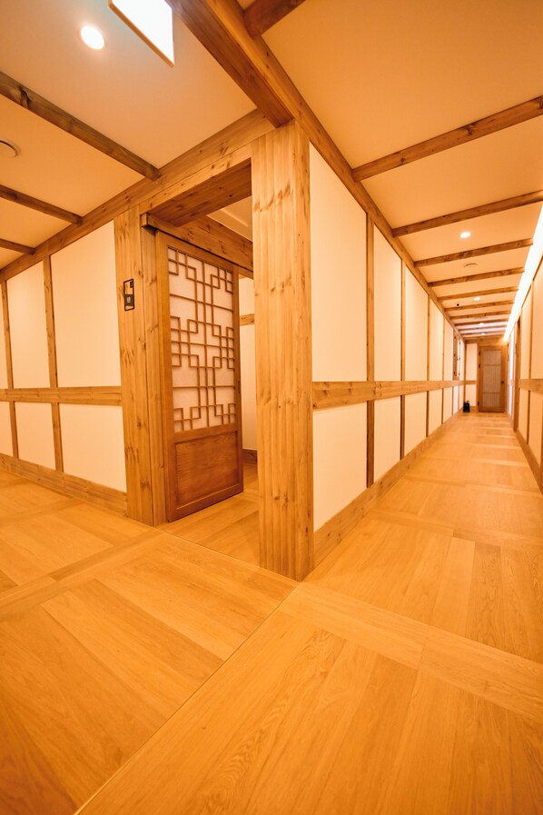 A corridor with wooden walls and floors, leading to a door with a geometric pattern. - Hanok Hotel DAAM (Seoul)