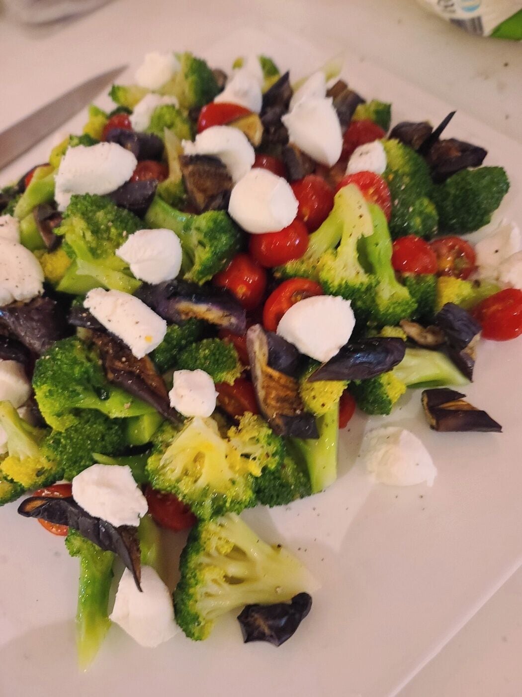 A plate of mixed vegetables including broccoli, cherry tomatoes, and eggplant.