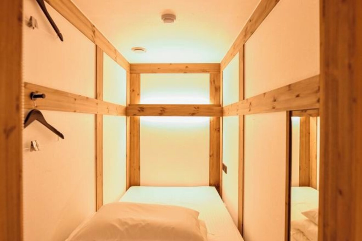 A narrow, wooden-framed room with a single bed and a door leading to another room.