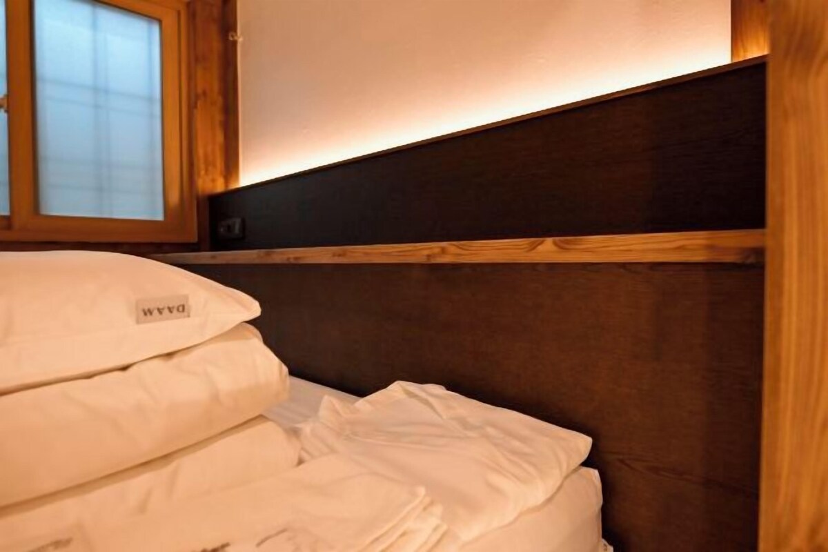 A bunk bed with a wooden headboard and a window with blinds.