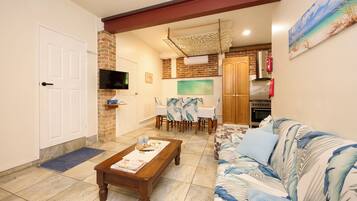A living room with a sofa, coffee table, and a dining area with a table and chairs.