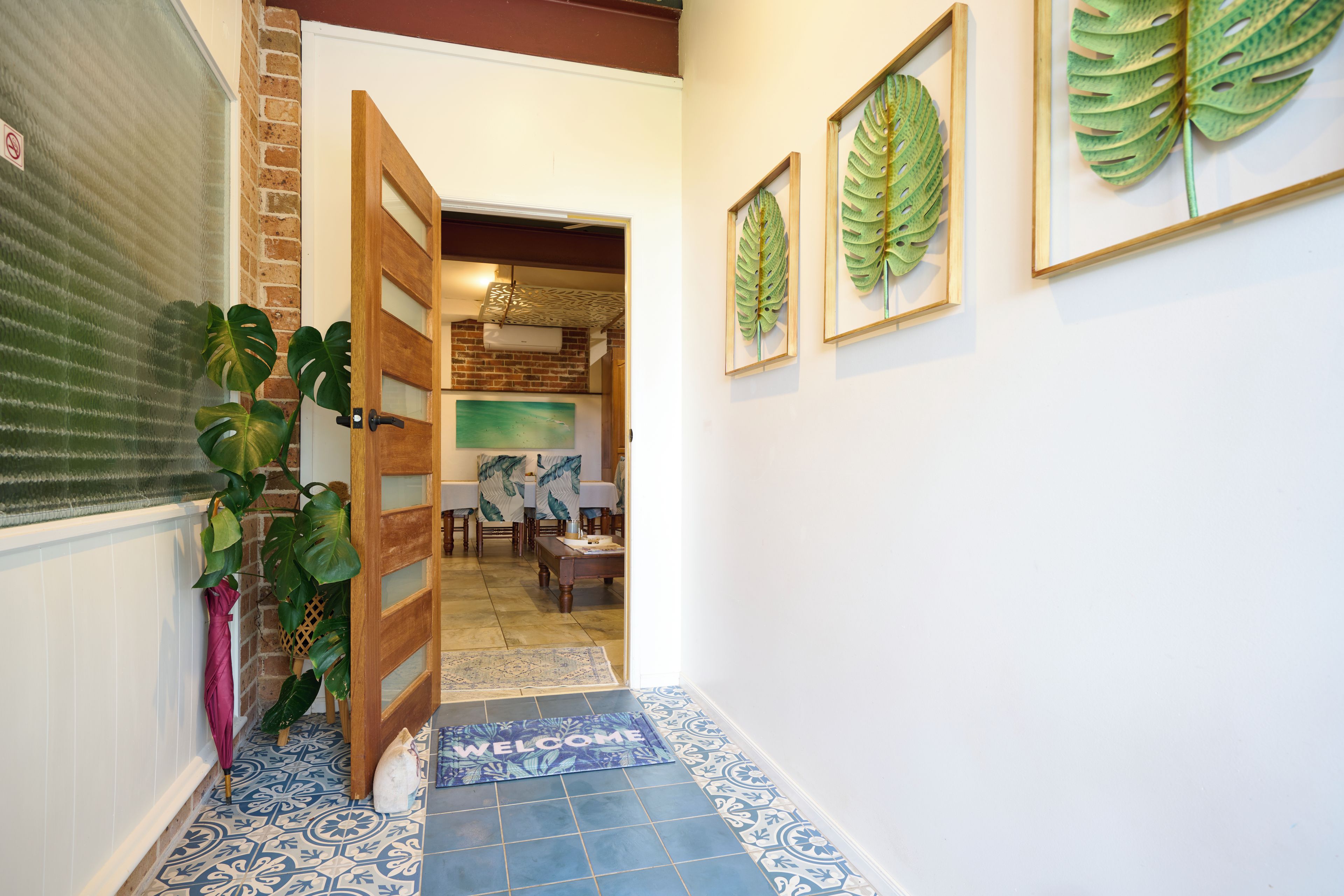 Un couloir avec un paillasson, une porte et un mur en briques.