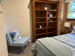 Une chambre à coucher avec un lit, une bibliothèque en bois, une chaise et une fenêtre donnant sur un beau paysage.