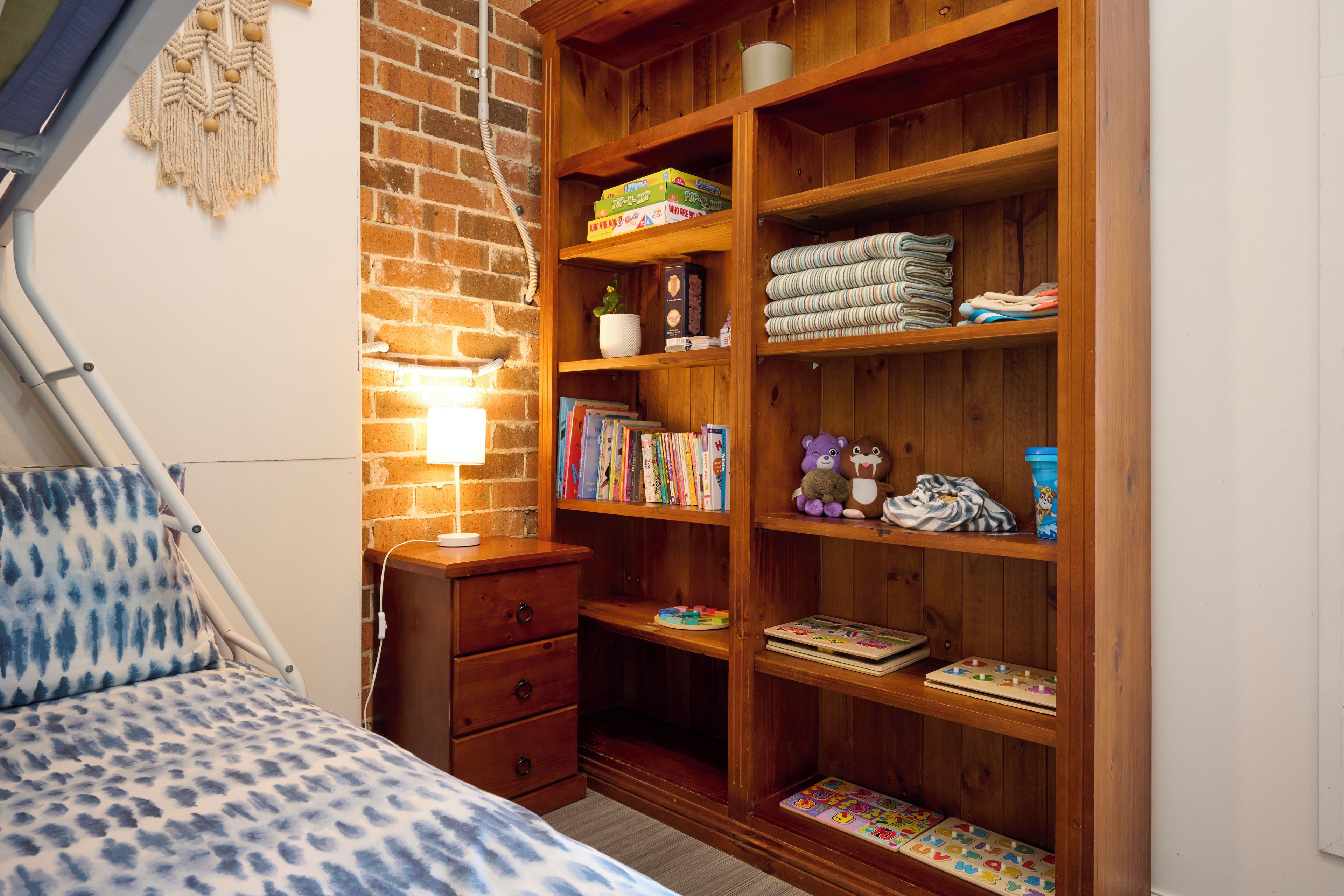 Un dormitorio con una cama, un armario de madera y una mesita de noche con una lámpara.