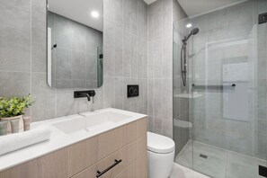 Features a large mirror, sink, and glass-enclosed shower area.