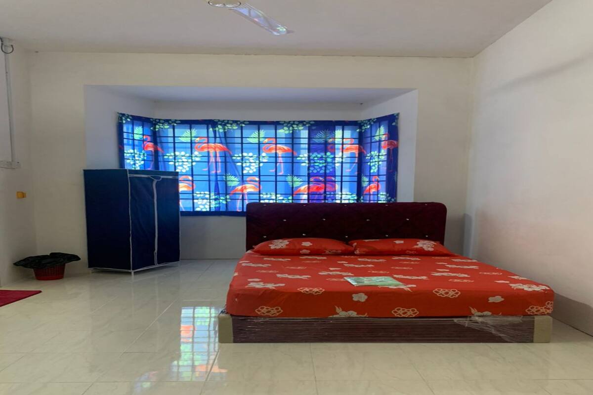 A bedroom with a bed, a window with a colorful pattern, a wardrobe, and a tiled floor.