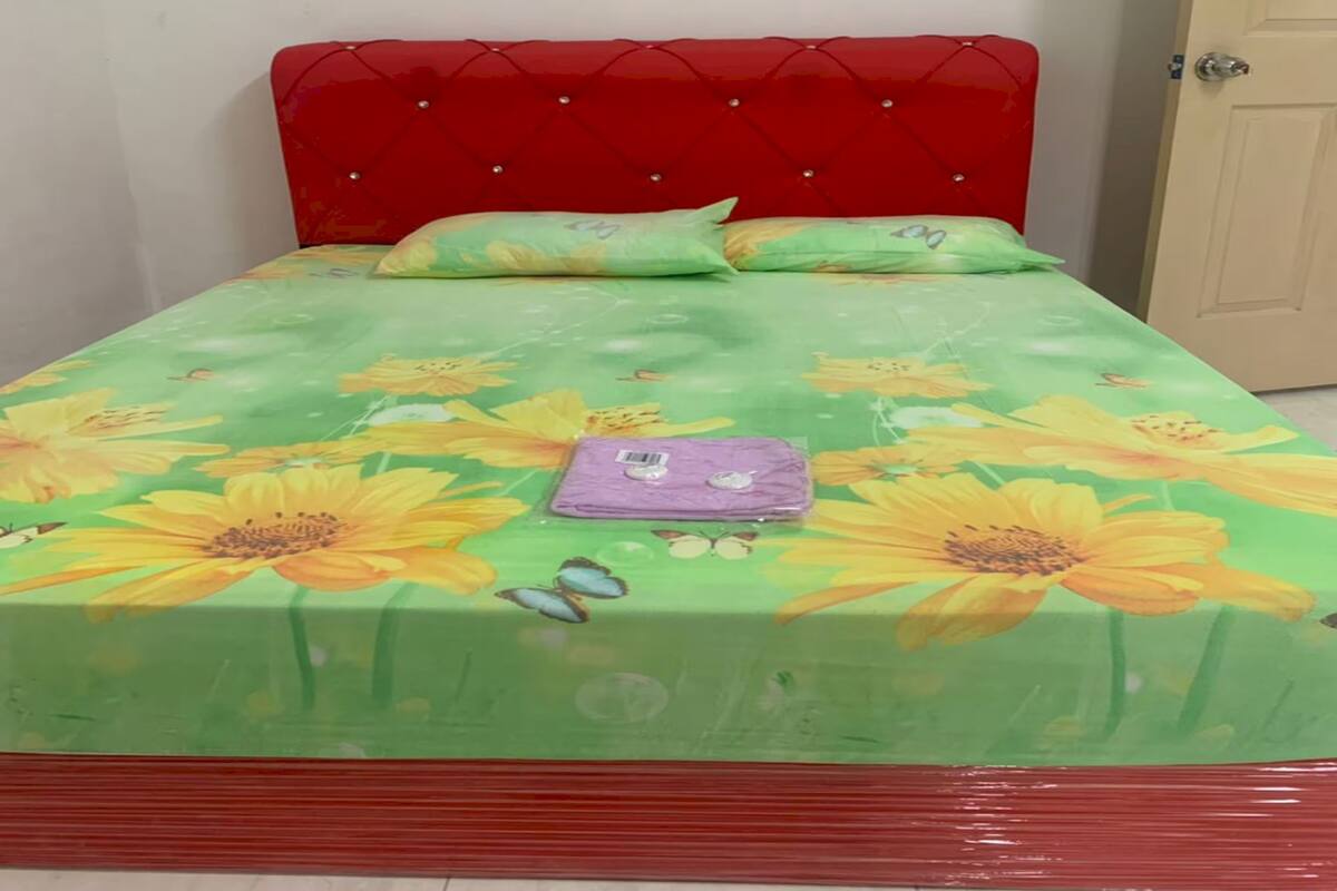 A bed with a floral bedspread, a red headboard, and a purple item on the bed.