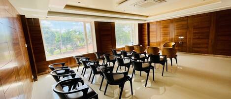 Un salón de conferencias con vistas a zonas verdes, paneles de madera e iluminación empotrada en el techo.