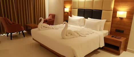 Habitación de hotel con una cama grande, dos lámparas de pared, una mesita de noche de madera y un sillón rojo.