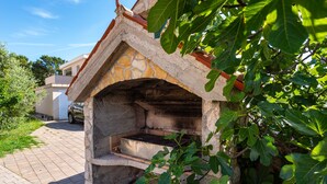 A stone oven structure with a brick roof, surrounded by greenery.