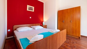 A room with a bed, a wardrobe, and a wall-mounted picture.