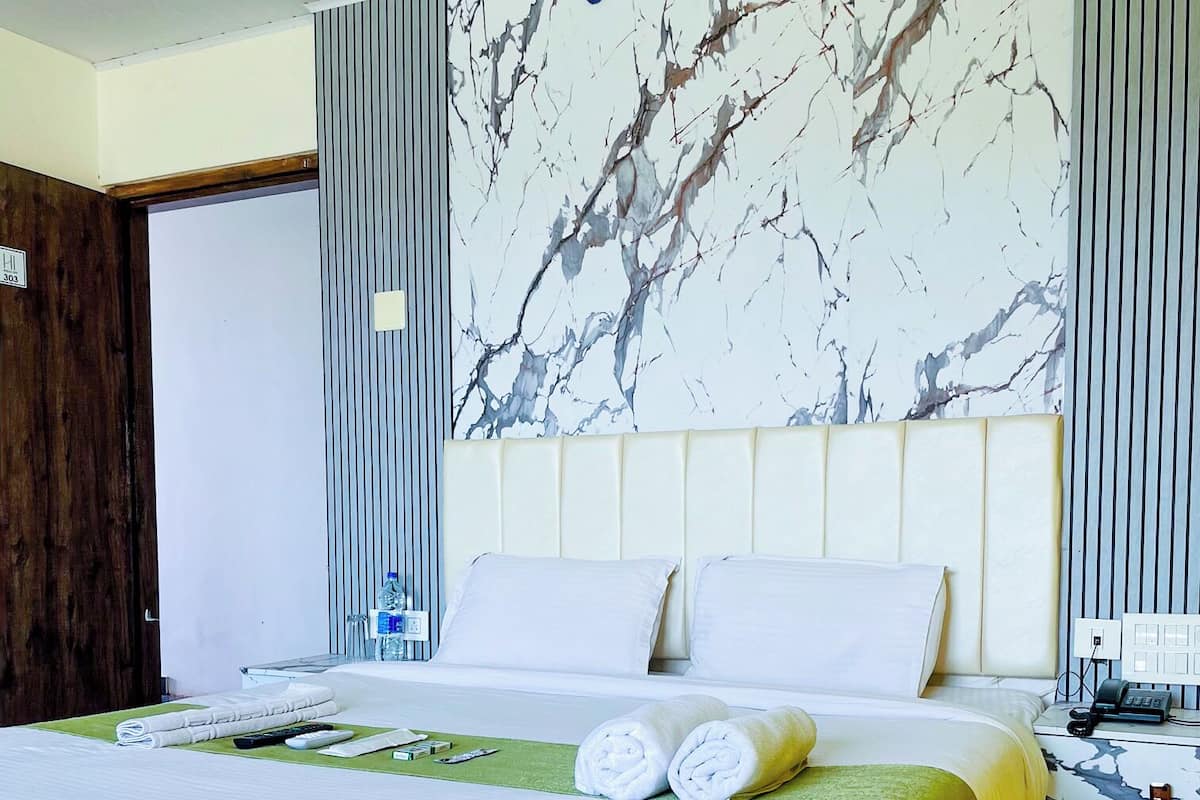 A hotel room with a marble-patterned headboard, a neatly made bed with white linens, and a green mat on the floor.