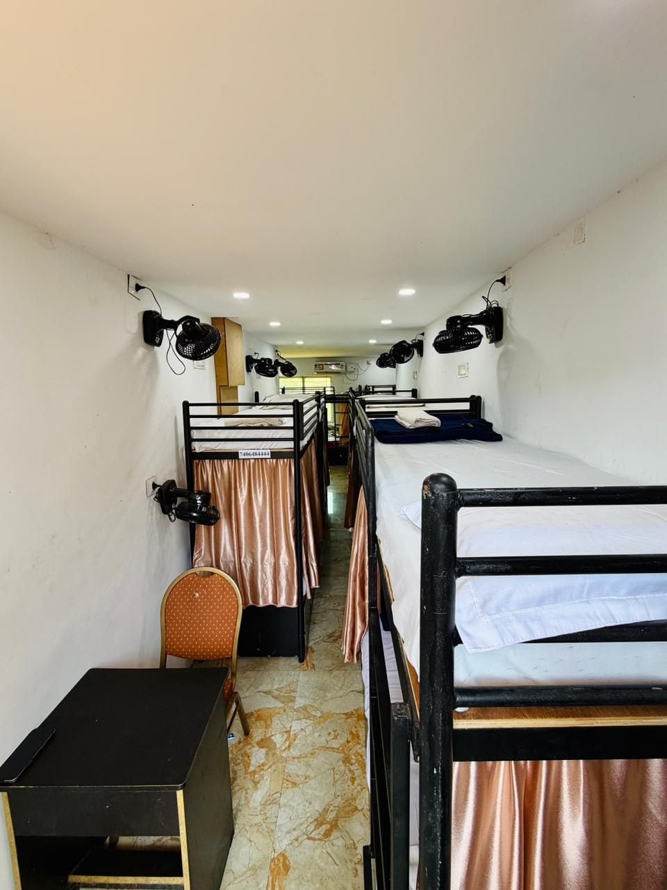 A corridor with bunk beds, a desk, and a chair.