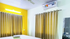 Habitación de hotel con cama, cortinas, ventilador de techo, botella de agua y piso con diseño de mármol.