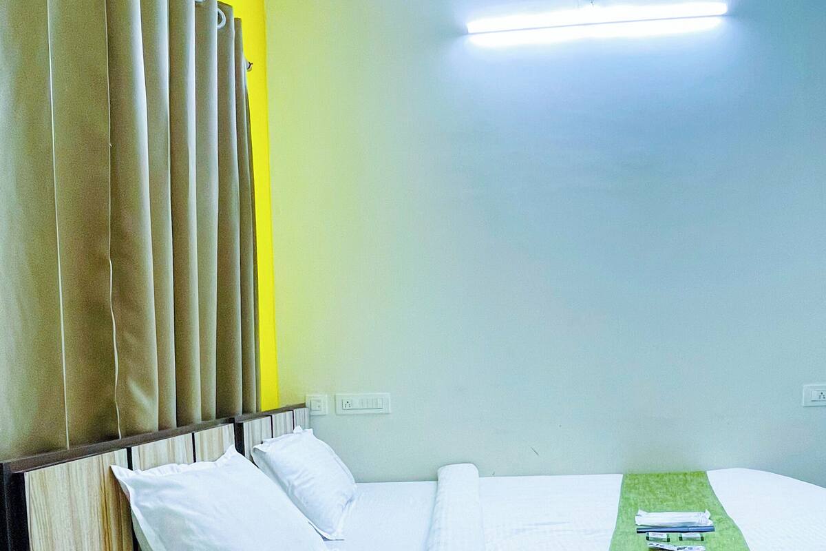 A hotel room with a bed, pillows, a green towel, and a headboard with curtains.