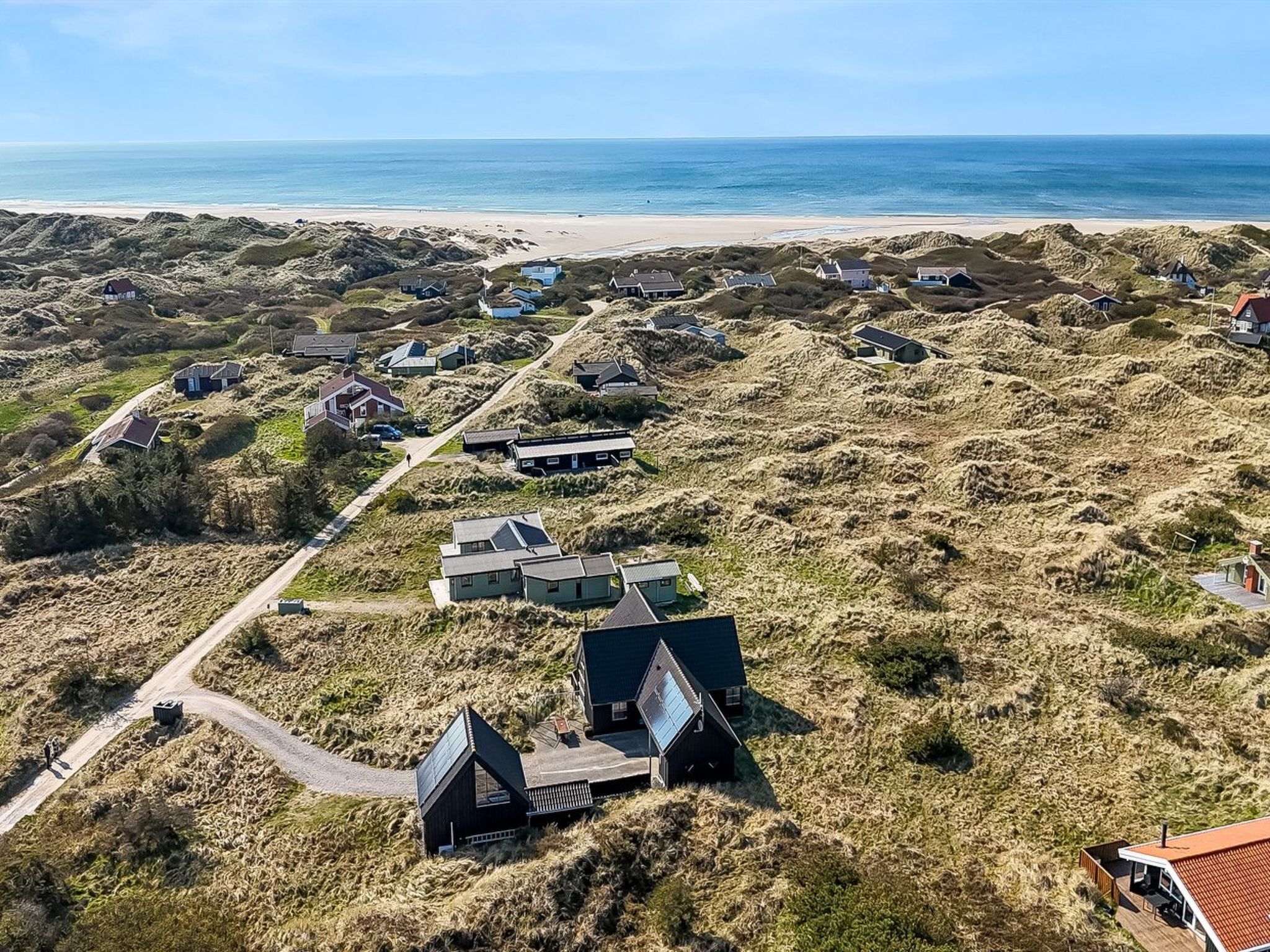 An aerial view of a coastal area with multiple houses and a beach in the background.