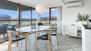 Una cocina moderna con una isla grande, armarios blancos y vistas al exterior.