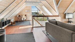 Amplio loft con techo alto, vigas de madera, zona de estar acogedora y un balcón con vistas.