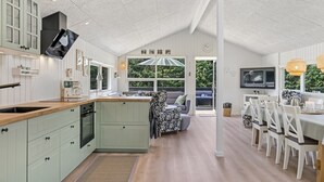 Een ruime keuken met een houten aanrecht, een zithoek met witte stoelen, en een groot raam dat zorgt voor natuurlijk licht.