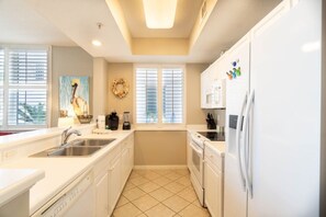 A modern kitchen with white cabinetry, a stainless steel sink, a dishwasher, and a refrigerator.