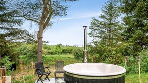 Un jacuzzi en un entorno de jardín con un banco y una pequeña mesa.