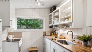 A modern kitchen with white cabinetry, a wooden countertop, a built-in sink, and a window overlooking greenery. - "Karl" - 4km from the sea by Interhome (Frederiksværk)