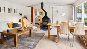 A cozy living room with a fireplace, a dining area with wicker chairs, and a kitchen visible through an open door. - "Karl" - 4km from the sea by Interhome (Frederiksværk)