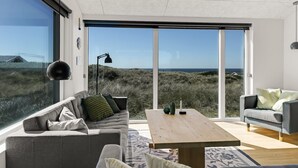 A modern living room with a large window, a sofa, a coffee table, and a lamp.