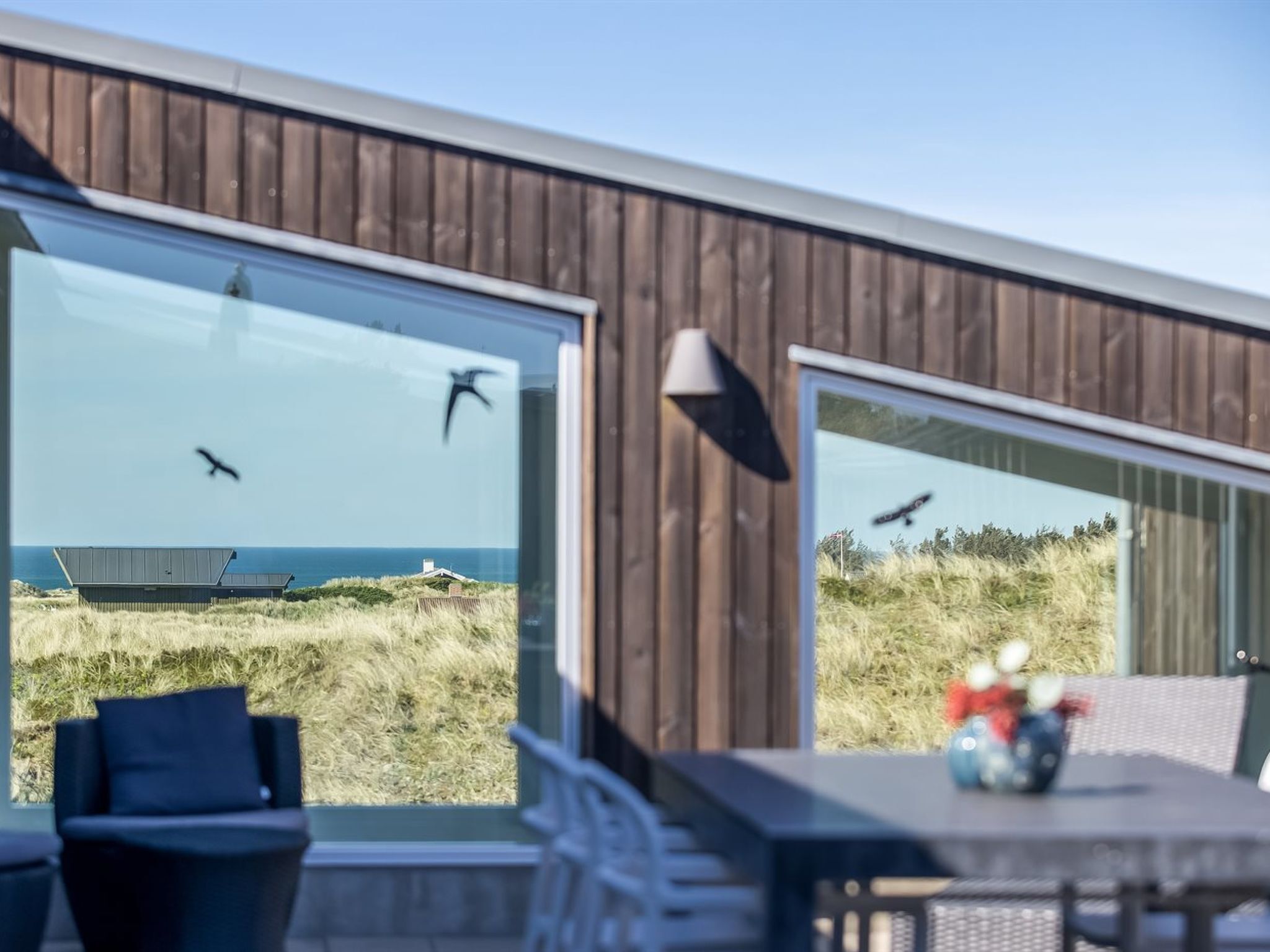 Ein modernes Gebäude mit großen Fenstern mit Blick auf Strand und Dünen.