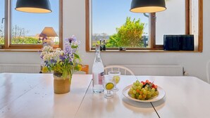 A dining area with a table set for two, featuring a plate of grapes, a bottle of water, and a vase of flowers. - "Santuzza" - 100m from the sea by Interhome (Svaneke)
