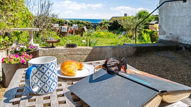 A table with a book, a mug, a croissant, and sunglasses. - "Santuzza" - 100m from the sea by Interhome (Svaneke)
