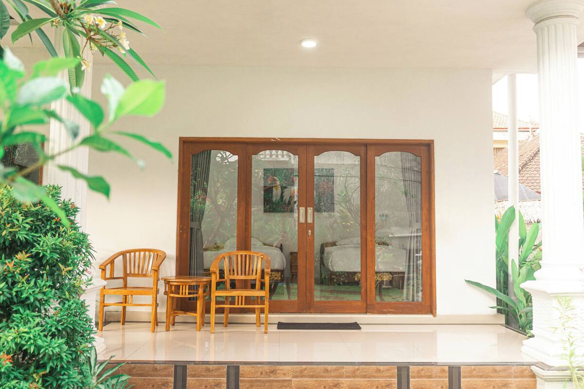 A wooden door with glass panels, two wooden chairs, and a small table in front.