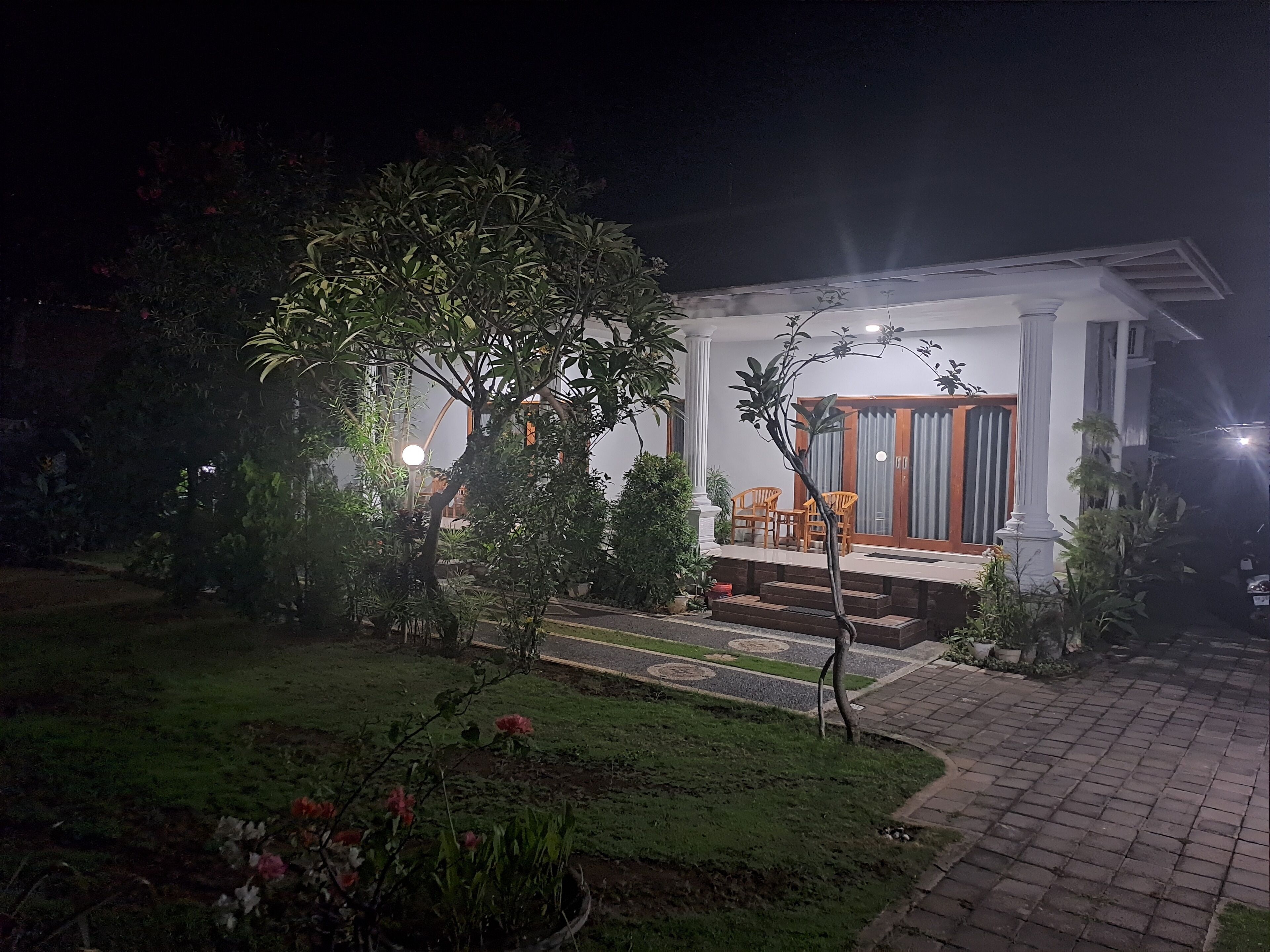 A house with a porch, a small garden, and a pathway leading to the entrance.