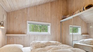 Une chambre avec un plafond en bois, un lit avec une literie blanche, une fenêtre et un miroir.