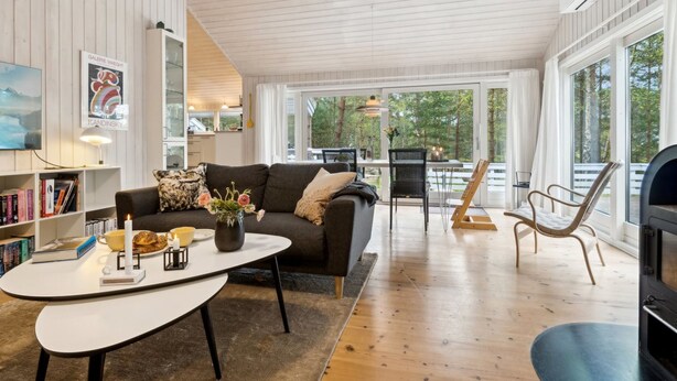 Un salon spacieux avec un canapé, une table basse et des fauteuils. On y trouve une cheminée, une bibliothèque et un tableau accroché au mur.