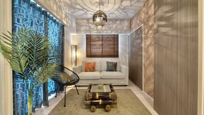 A modern living room with a sofa, a coffee table, a chair, and a large plant. - Branchera naha akebono premist R78 (Naha)