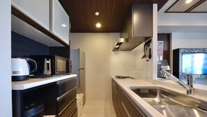 A modern kitchen with built-in appliances, a stainless steel sink, and a microwave. - Branchera naha akebono premist R78 (Naha)