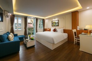 Una habitación de hotel con cama, sofá, escritorio y ventana con cortinas.