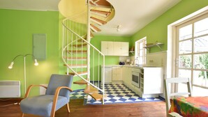A kitchen with a checkered floor, a spiral staircase, and a chair.
