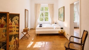 Ein Schlafzimmer mit Bett, einem Sessel, einem Fenster und Bildern an der Wand.