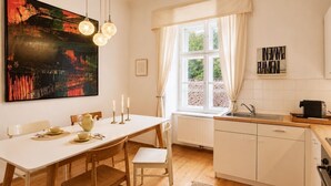 Eine moderne Küche mit weißen Schränken, einem Esstisch und einem großen Fenster mit Vorhängen.